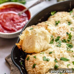 Parmesan bread bites in a cast iron pan with marinara sauce next to it.
